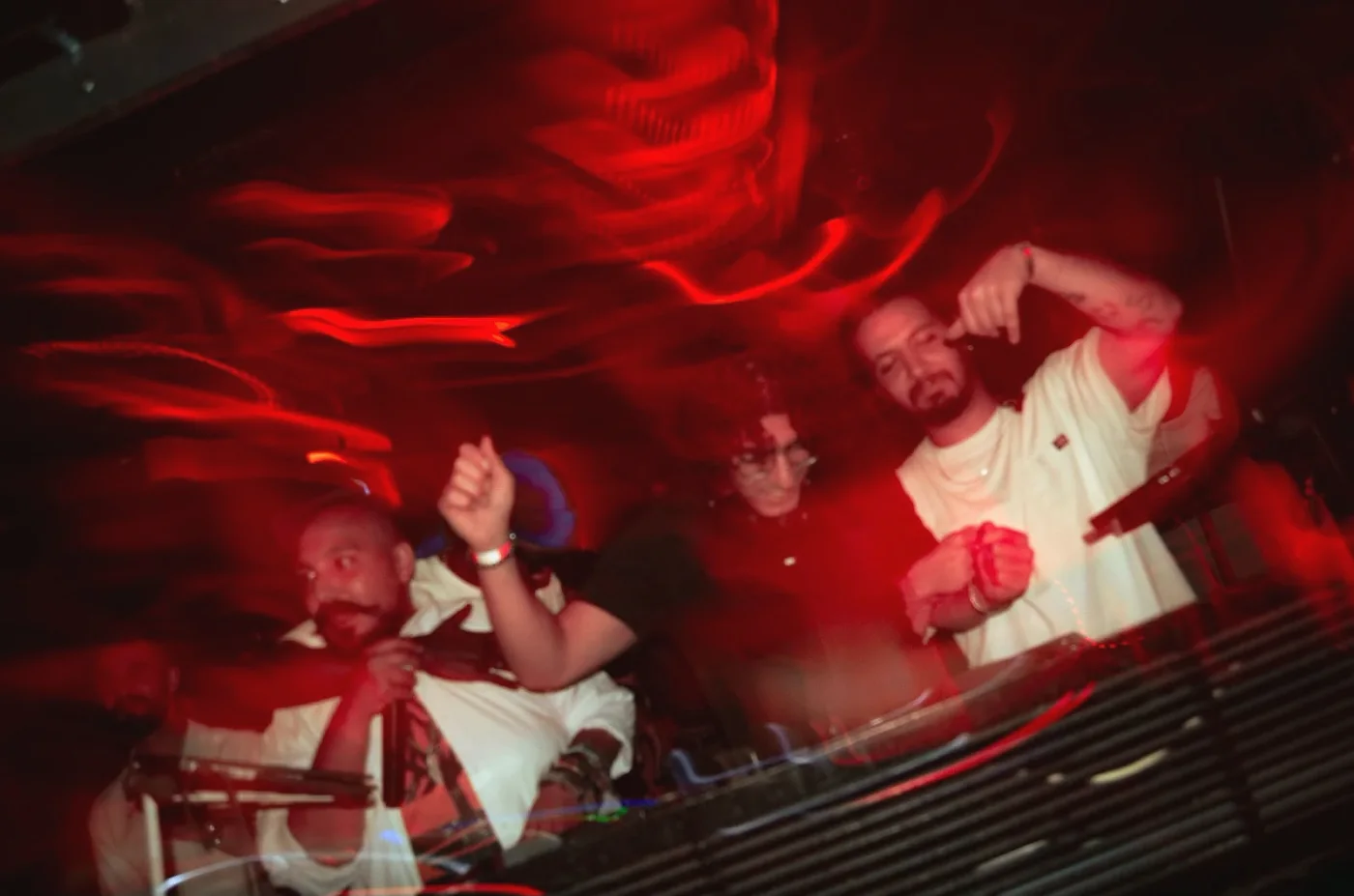 Anas and two others in the DJ booth, lit red