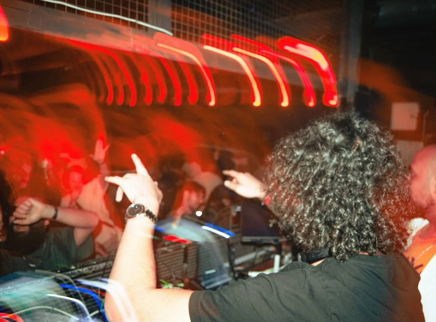 Anas from behind with both hands raised towards the crowd, red light trails overhead