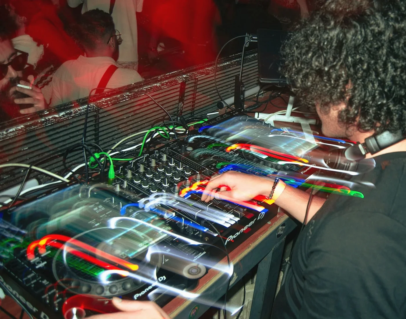 Close on a Pioneer DJ mixer with light trails as Anas adjusts it